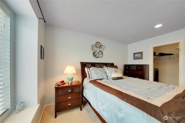 bedroom with a spacious closet, light carpet, and a closet