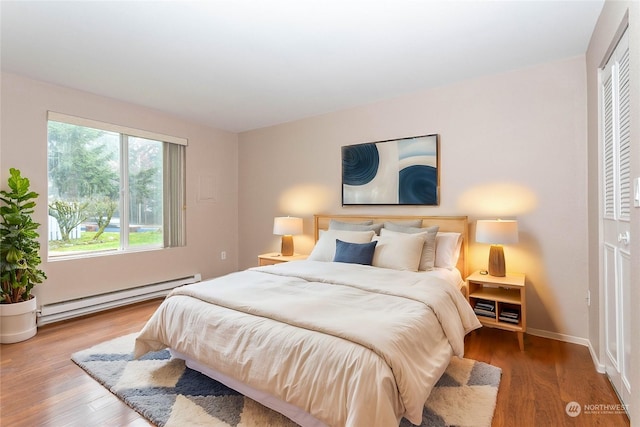 bedroom with wood-type flooring, a baseboard radiator, and a closet