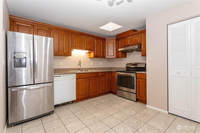 kitchen with light tile patterned flooring, stone countertops, stainless steel appliances, and sink