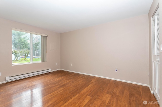 spare room featuring wood-type flooring and a baseboard radiator