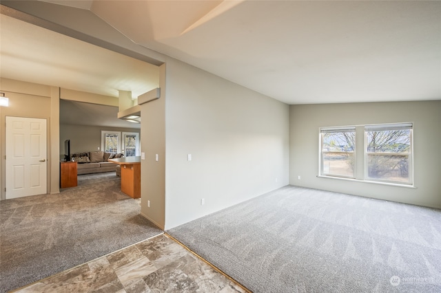 carpeted empty room with lofted ceiling