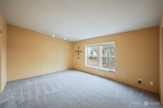 carpeted empty room featuring rail lighting