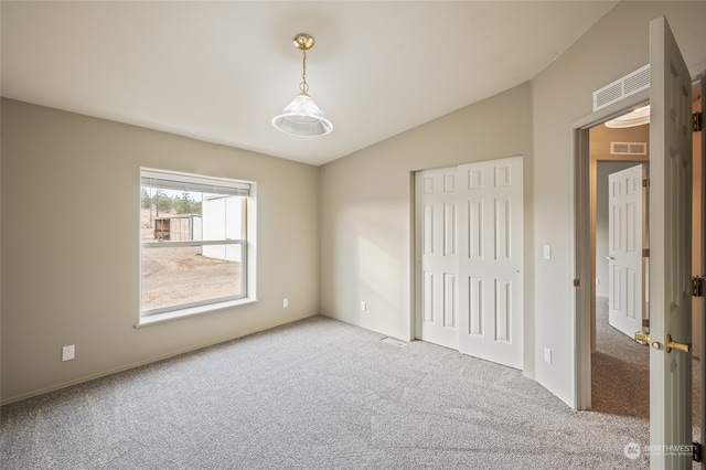 unfurnished bedroom with light colored carpet, a closet, and lofted ceiling