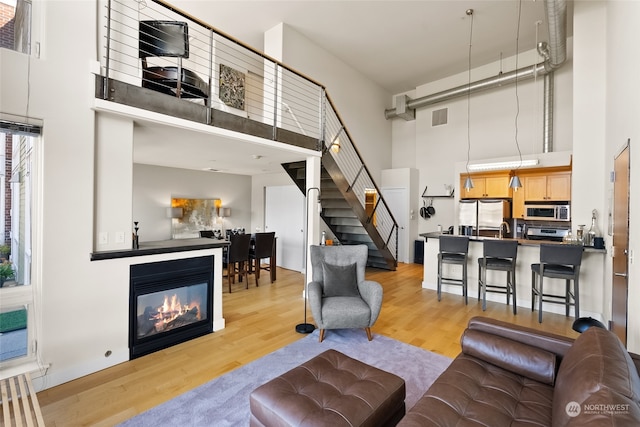 living room with light hardwood / wood-style floors and a towering ceiling