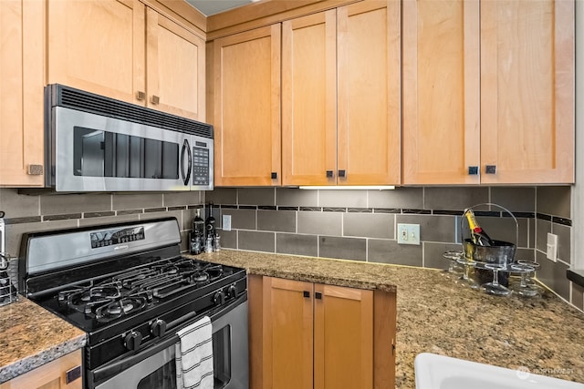 kitchen with decorative backsplash, light brown cabinets, light stone countertops, and stainless steel appliances