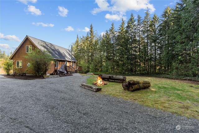 27525 W Lake Riley Rd, Arlington, WA 98223 - view of side of property featuring an outdoor fire pit, driveway, a deck, and a yard