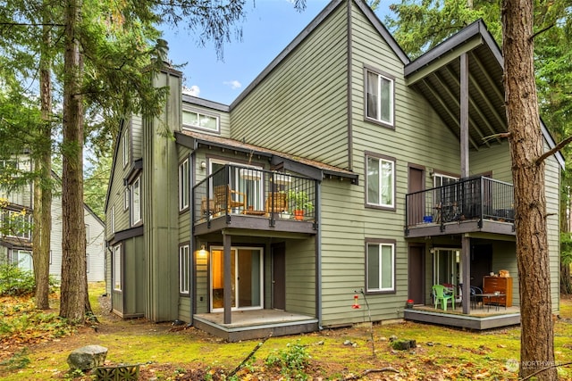 rear view of house with a chimney, a wooden deck, and a balcony