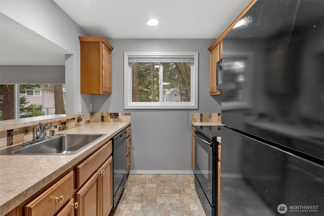 kitchen featuring black appliances, plenty of natural light, baseboards, and a sink