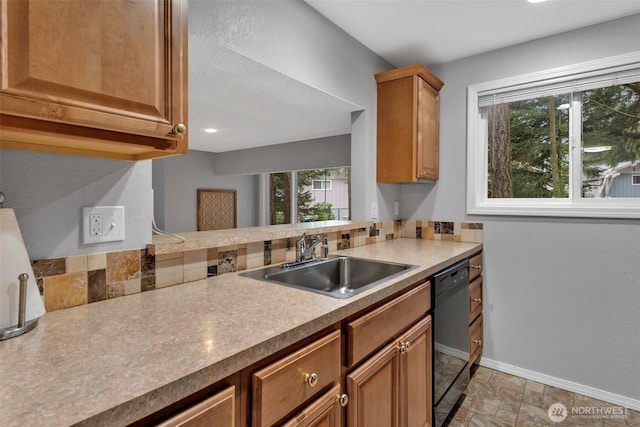 kitchen featuring baseboards, dishwasher, brown cabinets, light countertops, and a sink