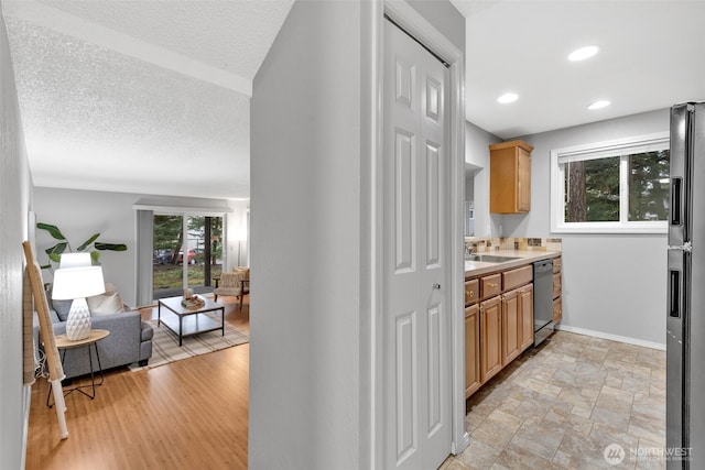 interior space featuring stainless steel dishwasher, open floor plan, a sink, baseboards, and black fridge