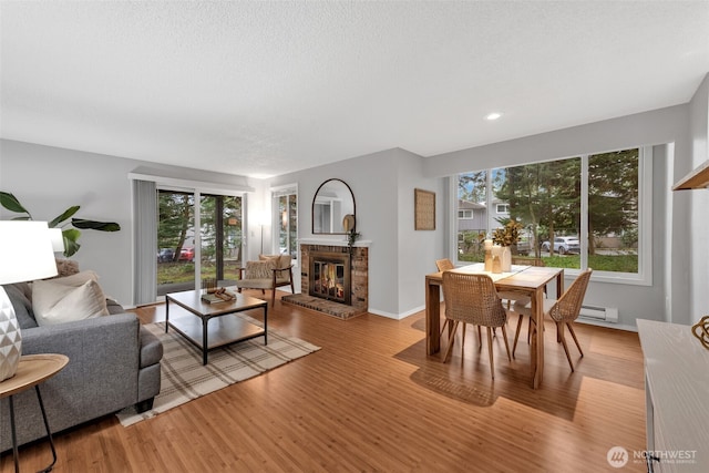 living area with a textured ceiling, recessed lighting, a fireplace, wood finished floors, and baseboards