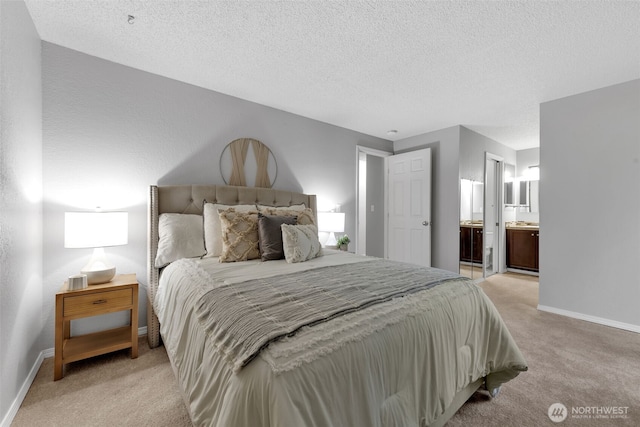 bedroom featuring light colored carpet, connected bathroom, a textured ceiling, and baseboards