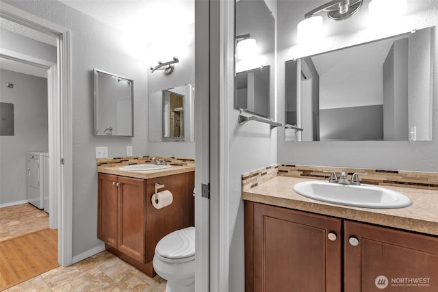 bathroom featuring toilet, vanity, baseboards, electric panel, and washer and clothes dryer