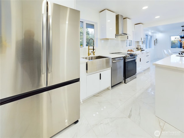 kitchen with marble finish floor, appliances with stainless steel finishes, modern cabinets, and wall chimney range hood