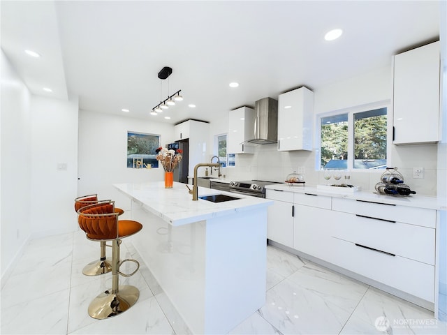 kitchen with marble finish floor, wall chimney exhaust hood, and modern cabinets