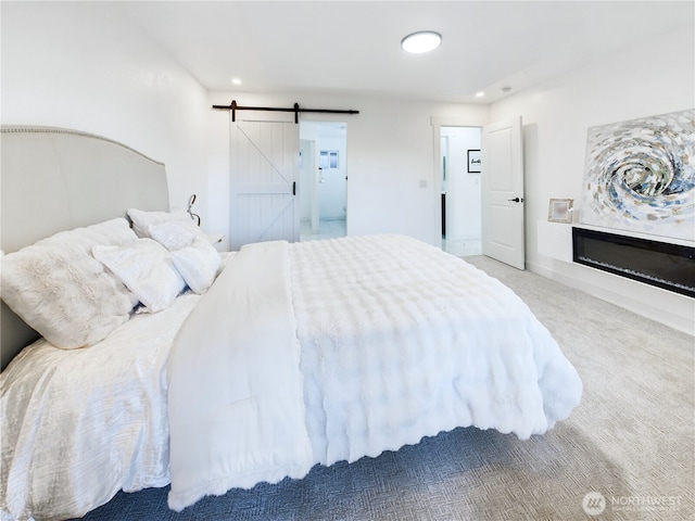 bedroom featuring ensuite bathroom, a barn door, recessed lighting, carpet floors, and a glass covered fireplace