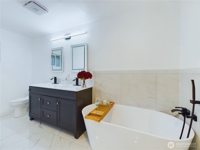 full bathroom with marble finish floor, double vanity, visible vents, a sink, and a freestanding tub