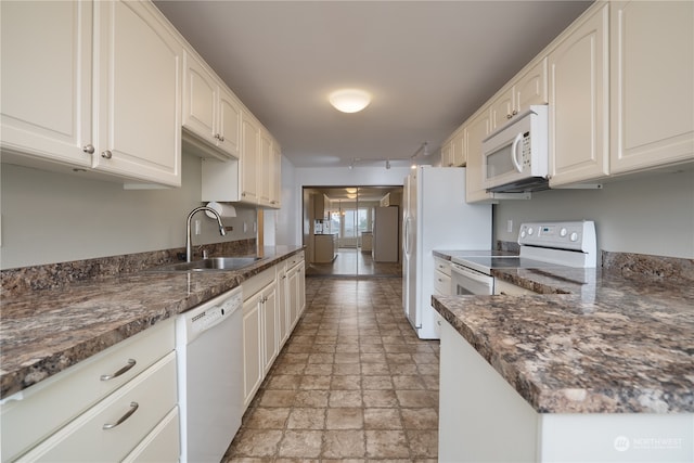 kitchen featuring white appliances, white cabinetry, dark stone countertops, and sink