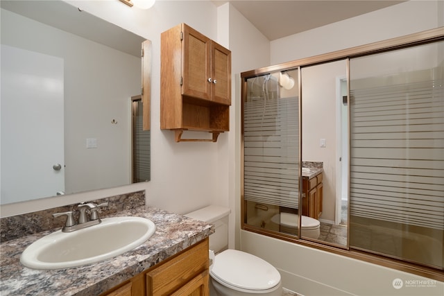 full bathroom featuring combined bath / shower with glass door, vanity, and toilet