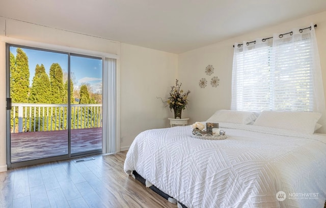 bedroom featuring access to outside, multiple windows, and hardwood / wood-style flooring