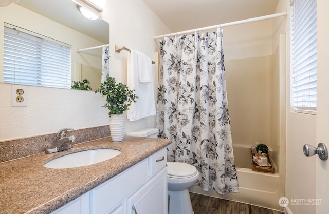 full bathroom featuring hardwood / wood-style floors, vanity, shower / tub combo, and toilet