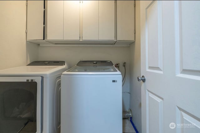 clothes washing area with separate washer and dryer and cabinets