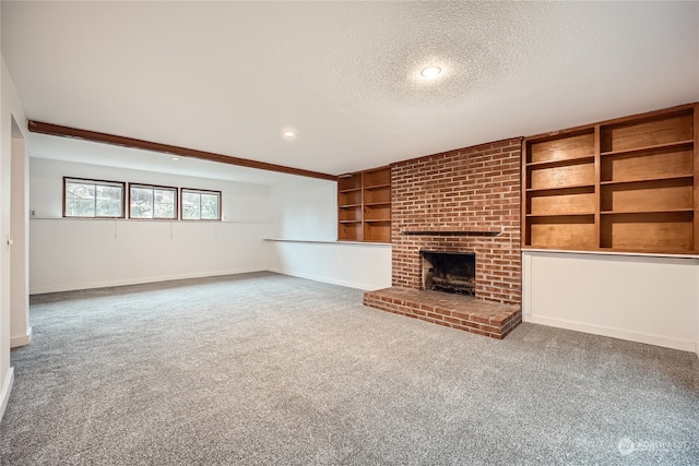 unfurnished living room with carpet flooring, built in features, a fireplace, and a textured ceiling