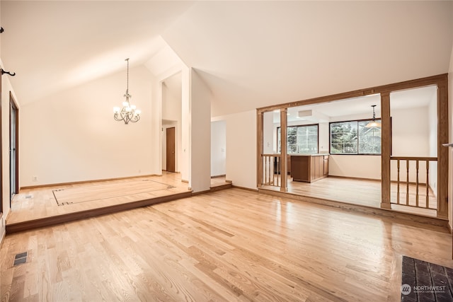 empty room featuring light wood-type flooring, high vaulted ceiling, and an inviting chandelier