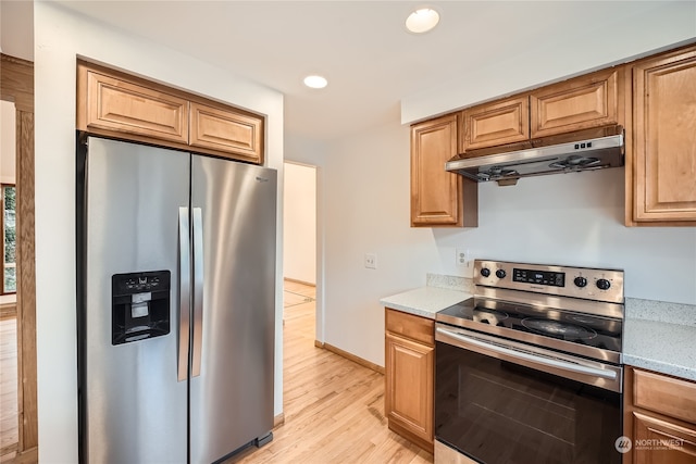 kitchen with light stone countertops, light wood-type flooring, and appliances with stainless steel finishes