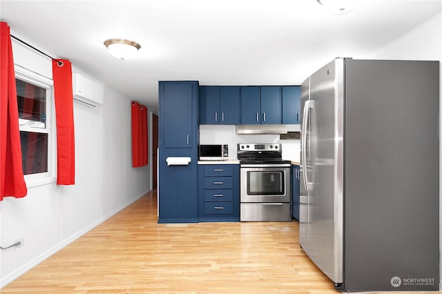 kitchen with a wall unit AC, blue cabinets, appliances with stainless steel finishes, and light hardwood / wood-style flooring