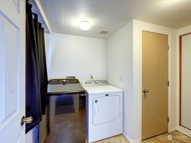 washroom with a textured ceiling and washer and clothes dryer