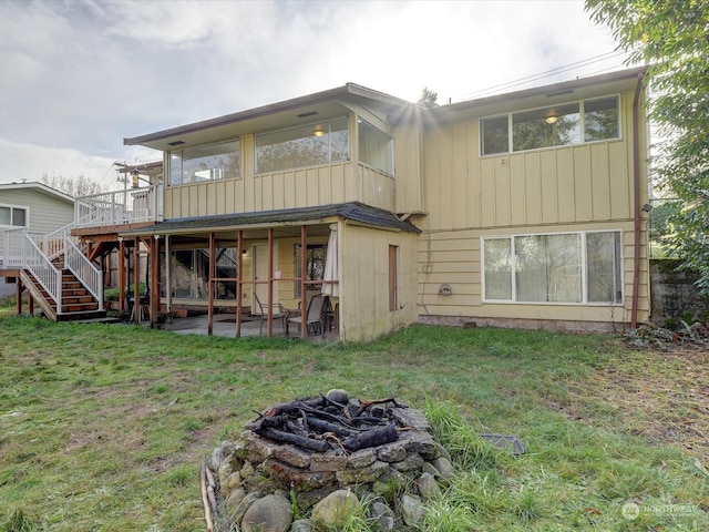 back of property featuring a patio area, a yard, a fire pit, and a deck