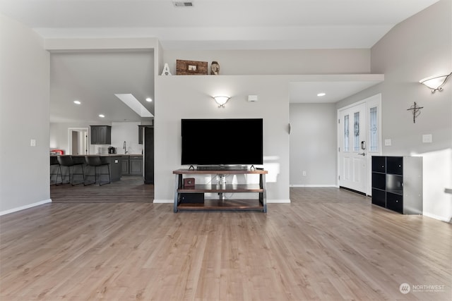 living room with light hardwood / wood-style flooring, french doors, and sink