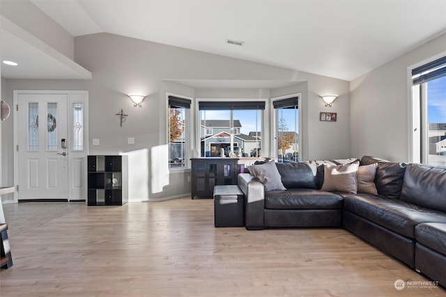 living room featuring light hardwood / wood-style floors, vaulted ceiling, and a healthy amount of sunlight