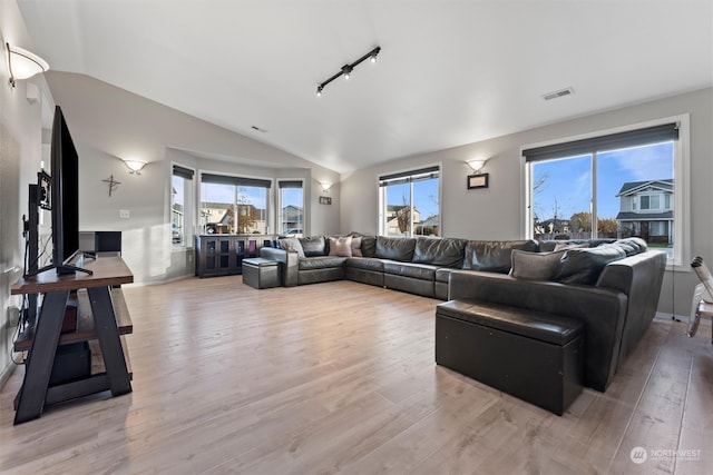 living room featuring light hardwood / wood-style floors, vaulted ceiling, and a wealth of natural light