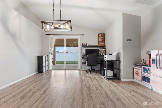 office space with light hardwood / wood-style floors, vaulted ceiling, and an inviting chandelier