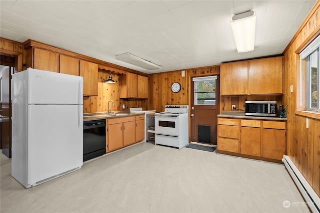 kitchen with wooden walls, sink, white appliances, and a baseboard heating unit