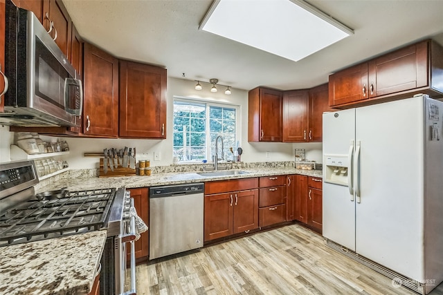 kitchen featuring light stone countertops, sink, light hardwood / wood-style floors, and appliances with stainless steel finishes