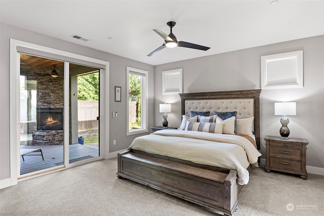 bedroom with access to exterior, light carpet, ceiling fan, and a fireplace