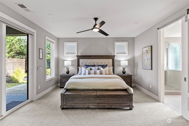 carpeted bedroom with access to outside, a barn door, ensuite bathroom, and ceiling fan