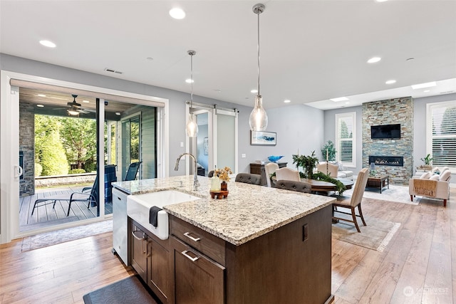 kitchen with light wood-type flooring, a barn door, decorative light fixtures, and ceiling fan