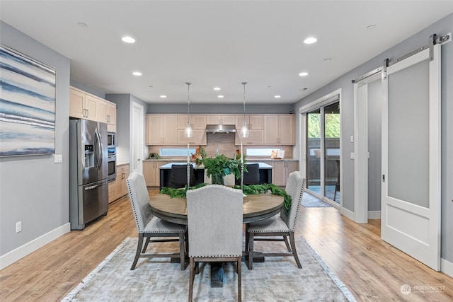 dining area with a barn door and light hardwood / wood-style flooring