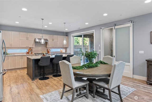 dining space with a barn door and light hardwood / wood-style floors