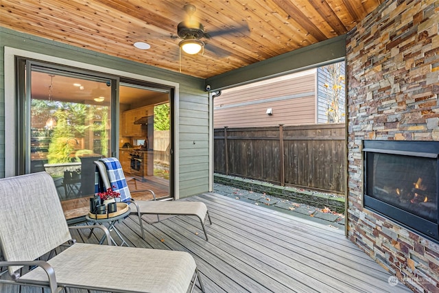 wooden deck featuring ceiling fan and exterior fireplace