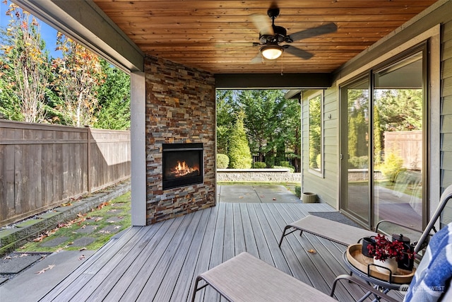 wooden terrace with ceiling fan and an outdoor stone fireplace