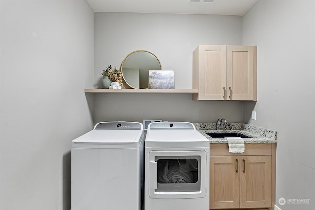 washroom featuring cabinets, sink, and washer and dryer