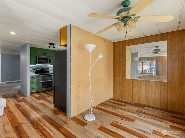 interior space with ceiling fan, wooden walls, and light hardwood / wood-style flooring