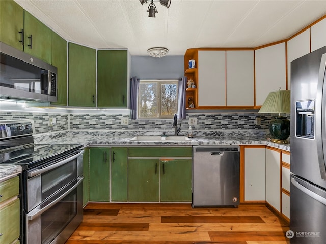 kitchen featuring sink, green cabinetry, appliances with stainless steel finishes, white cabinets, and light wood-type flooring