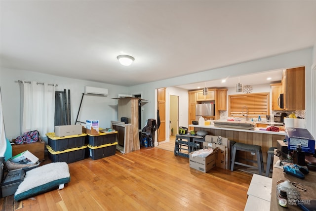 living room with a wall mounted air conditioner and light wood-type flooring