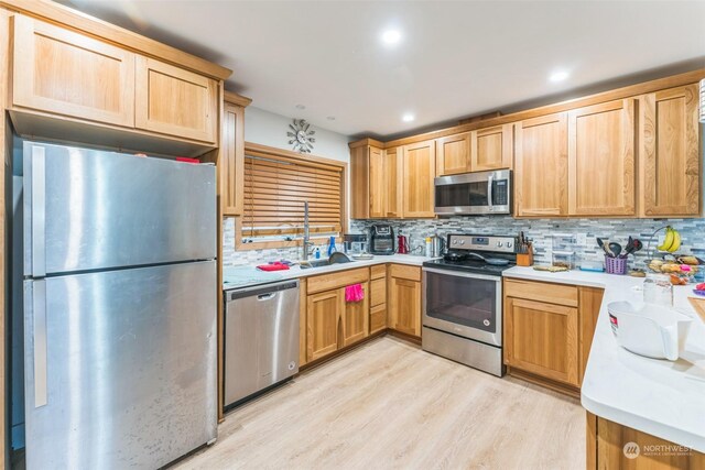 210 Stevens Ave, Coulee Dam, WA 99116 - kitchen with appliances with stainless steel finishes, a sink, decorative backsplash, light wood-style flooring, and light countertops